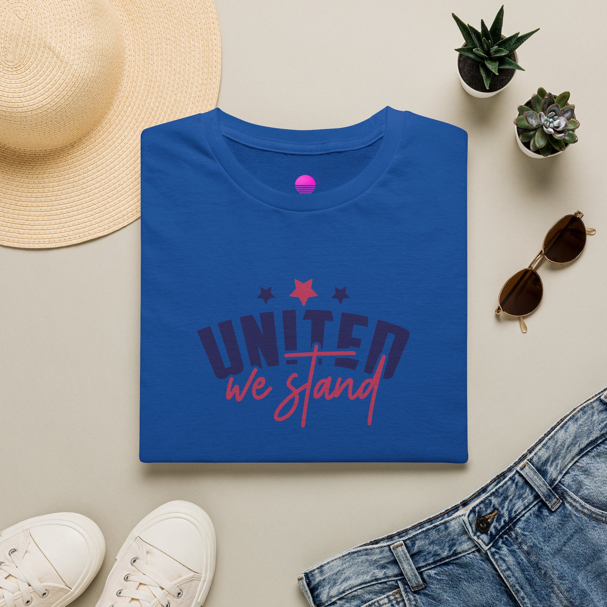 July 4th patriotic t-shirt displayed on a flat lay with a straw hat, sunglasses, and plants.